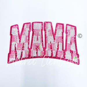 May include: Pink and white sequined patch with the word "MAMA" in a bold, arched font.