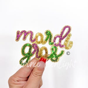 May include: A gold, green, and purple sequined patch that reads "Mardi Gras".