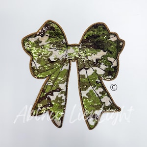 May include: A large green and gold sequined bow with a camouflage pattern. The bow is outlined in gold thread.