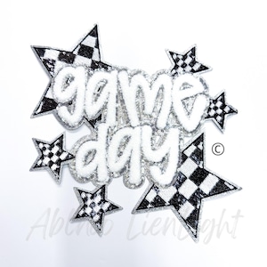 May include: White and silver iron-on patch with the words "game day" in a stylized font. The patch is surrounded by five black and white checkered stars.