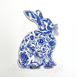 May include: Blue and white embroidered iron-on patch of a rabbit with floral details.