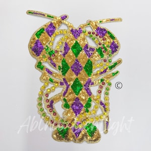 May include: A gold, green, and purple sequined lobster applique with a diamond pattern. The lobster is wearing a beaded necklace.