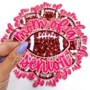 May include: Pink and brown iron-on patch with the text "Mom of a Senior" and a sequined football design.