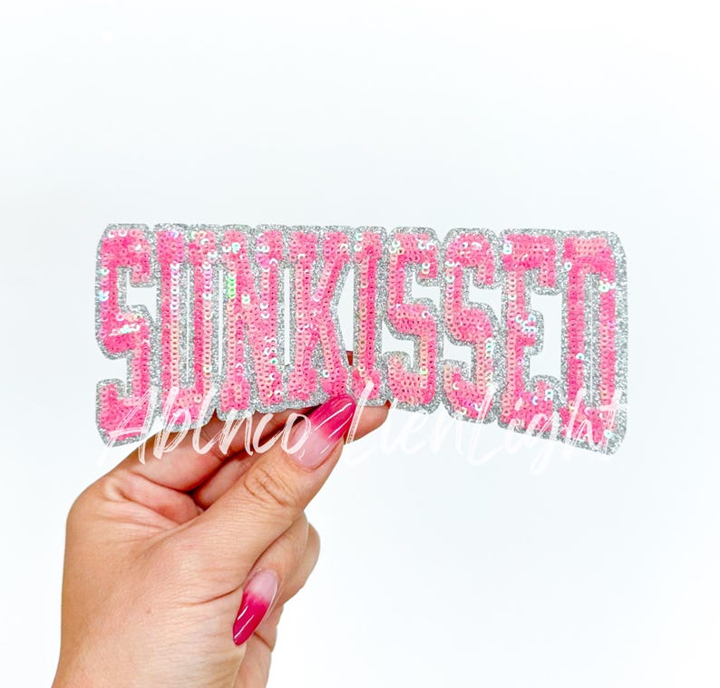 May include: Pink sequin patch with the word "SUNKISsed" in white letters.