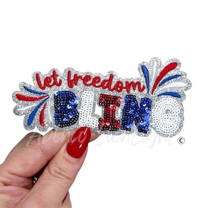 May include: A patriotic sequined patch with the words "Let Freedom BLING" in red, white, and blue. The patch has a silver glitter border and is shaped like a burst of fireworks. The word "BLING" is in blue and red sequins.