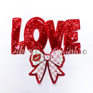 May include: Red sequin LOVE letters with a pink and white sequin bow with a red lip print in the center.