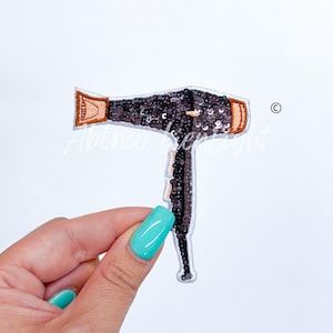 May include: A black and brown sequined hair dryer iron-on patch. The patch is designed to look like a hair dryer with a brown handle and a black barrel.