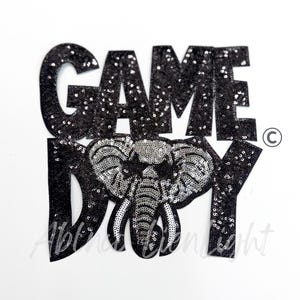 May include: Black sequined "GAME DAY" patch with a silver sequined elephant design. The patch is on a white background. The text is in large, bold letters.