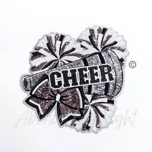 May include: A silver and black sequined iron-on patch with a cheerleader megaphone, pom-poms, and a bow. The megaphone has the word "CHEER" written on it.