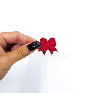May include: A red glitter bow with a satin finish. The bow is perfect for adding a festive touch to any craft project.