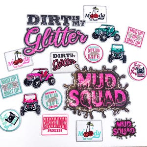 Pode incluir: Uma cole&ccedil;&atilde;o de patches bordados com v&aacute;rios designs e texto. Os patches apresentam frases como "Dirt My Glitter" e "Mud Squad", juntamente com imagens de ve&iacute;culos off-road e cerejas. As cores incluem rosa, preto e azul-petr&oacute;leo.