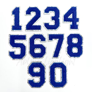 May include: Ten blue felt iron-on numbers with a silver glitter outline. The numbers are 1, 2, 3, 4, 5, 6, 7, 8, 9, and 0.