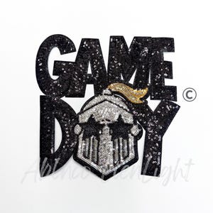 May include: Black sequined "GAME DAY" patch with a silver and gold helmet design. The patch is on a white background. The text and helmet are outlined in black sequins.