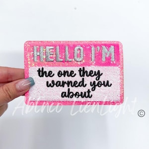 May include: Pink and white iron-on patch with the text "HELLO I'M the one they warned you about".