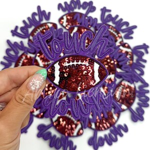 May include: Purple felt patches with the words "touch down" and a football design with red sequins.