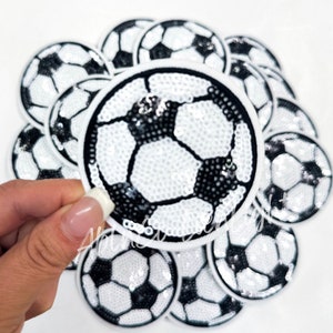 May include: A set of 10 black and white soccer ball patches with sequins. The patches are round and have a white background with a black soccer ball design. The patches are perfect for adding a sporty touch to clothing, bags, or other crafts.
