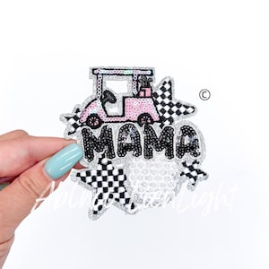 May include: A sparkly pink golf cart with golf clubs in the back, surrounded by black and white checkered stars and the word "MAMA" in black sequins.