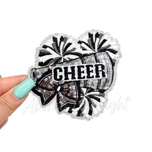 May include: Black and white cheerleading pom poms with silver sequins and the word "CHEER" in black embroidery.