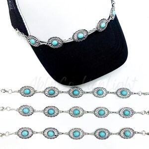 May include: Five turquoise and silver chain bracelets with a turquoise stone in each link. The bracelets are shown on a white background with a black and white baseball cap in the background.