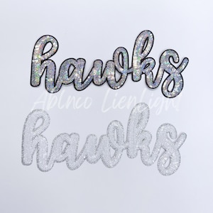 May include: Two versions of the word "Hawks" in silver sequins. The top version is black with silver sequins, and the bottom version is white with silver sequins.