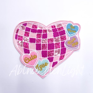 May include: Pink heart-shaped sequin patch with four smaller heart-shaped patches attached. The smaller patches have the words "Be Mine", "Kiss Me", "Cute", and "Love" written on them.