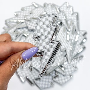 May include: A pack of silver and white checkered lightning bolt iron-on patches.