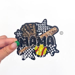 May include: A black and white checkered fabric patch with the word "MAMA" in black sequins. The patch also features a gold baseball bat, a gold baseball glove, and a yellow and red baseball.