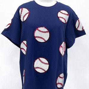 May include: A navy blue t-shirt with white and red baseballs made of sequins.