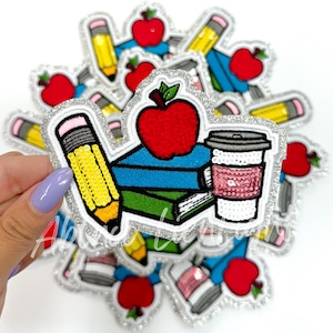 May include: A set of iron-on patches featuring a stack of books, a red apple, a pencil, and a coffee cup. The patches are decorated with sequins and have a silver glitter border.