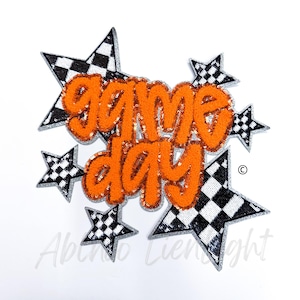 May include: Orange felt "game day" lettering with black and white checkered star accents.