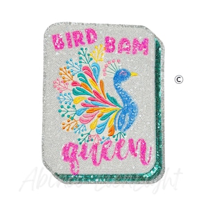 May include: A rectangular sequined patch with a peacock design. The peacock is blue with a colorful tail. The text "BIRD BAM QUEEN" is in pink sequins. The patch has a silver background and a green border.