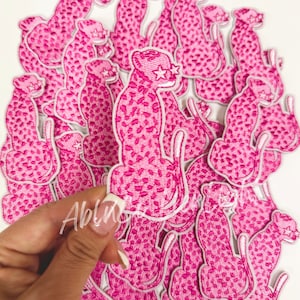 May include: A pile of pink cheetah print iron-on patches with white outlines and a white star on each cheetah's eye.