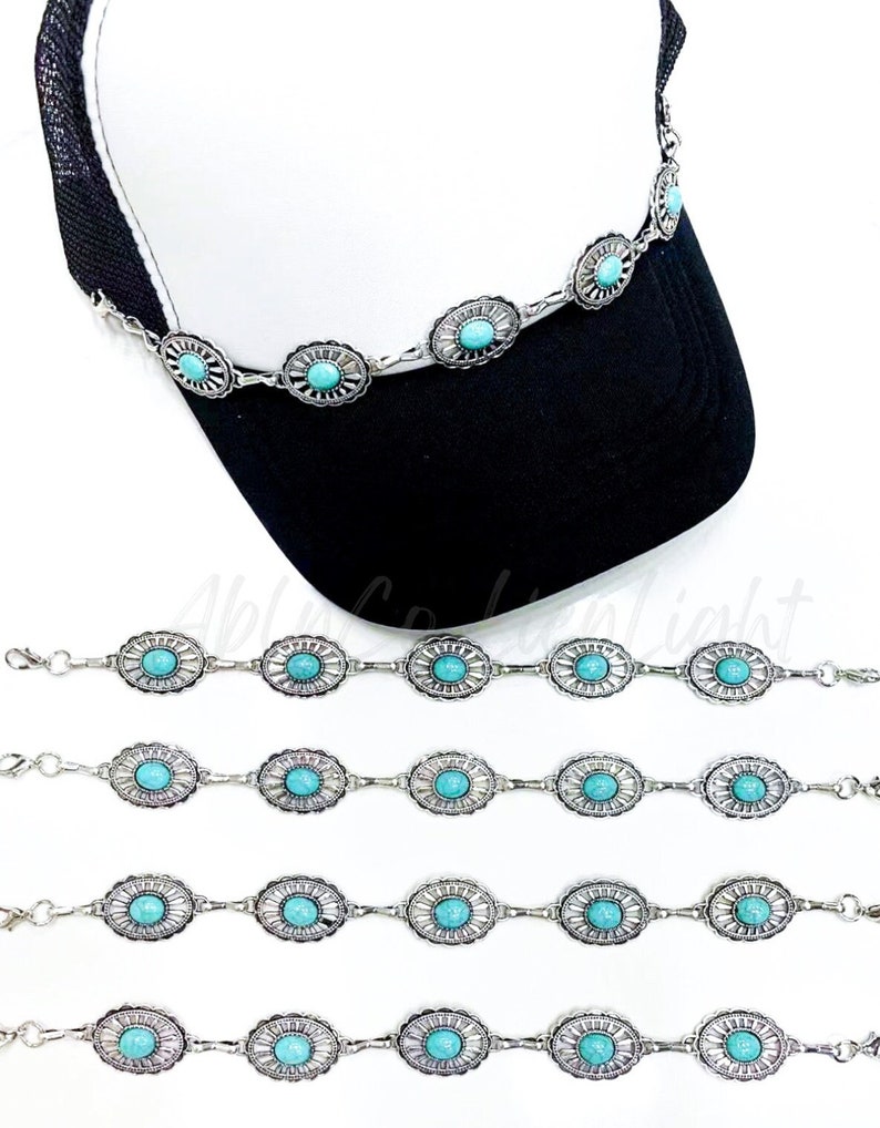 May include: Four silver chains with turquoise stones, each chain has five stones and is approximately 10 inches long. The chains are laid out in a row on a white surface. A black and white baseball cap with a white mesh top is in the background.