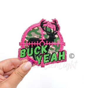 May include: Pink and green embroidered patch with a deer in a target and the text "BUCK YEAH".