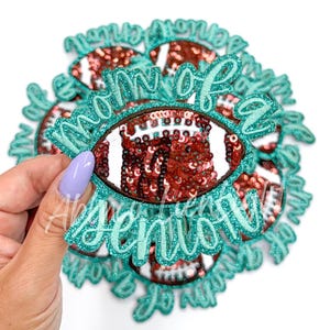 May include: A set of teal and brown iron-on patches with the text "Mom of a Senior" and a sequined football design.