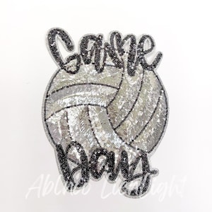 May include: A silver and black sequined iron-on patch with a volleyball and the words "Game Day".