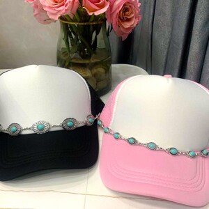 May include: Two trucker hats with turquoise stone embellishments. One hat is black with a white crown and the other is pink with a white crown.