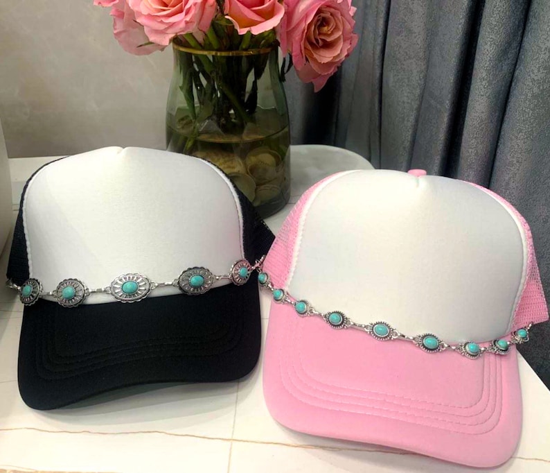 May include: Two trucker hats with turquoise stone embellishments. One hat is black with a white crown and the other is pink with a white crown.