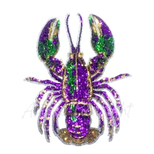 May include: A sequined lobster design in purple, green, and gold. The lobster has large claws and multiple legs, with a detailed pattern of sequins. The design is set against a white background.