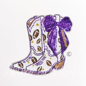 May include: A white sequined cowboy boot patch featuring a repeating pattern of brown footballs and gold stars. A large, purple sequined bow is attached to the top, with the word TOUCHDOWN embroidered in gold thread on one of the bow's tails.