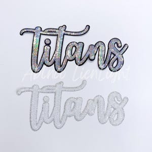 May include: Two iron-on patches with the word "Titans" in a sparkly silver and black font. The top patch is black with silver sequins and the bottom patch is white with silver sequins.