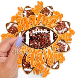 May include: A set of 10 iron-on patches featuring a football with sequins and the text "game day" in orange.