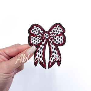 May include: A red and white checkered bow with a burgundy outline. The bow is made of fabric and has a shiny finish.