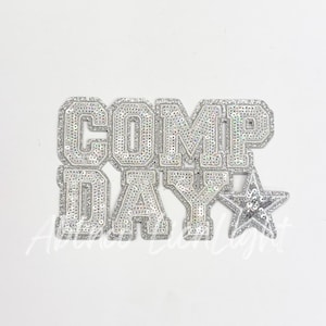 May include: A silver sequined iron-on patch with the words "COMP DAY" and a silver star.
