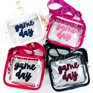 Puede incluir: Cuatro bolsos de bandolera de pl&aacute;stico transparente con correas de diferentes colores y parches de "game day". Los bolsos son blancos, rosas, rojos y negros.