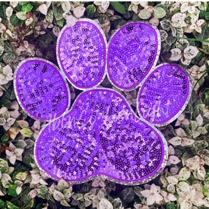 May include: Purple paw print made of sequins with a silver outline.