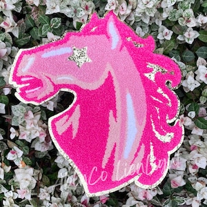 May include: Pink glitter horse head with a gold glitter star on its forehead. The horse head is a decorative item.