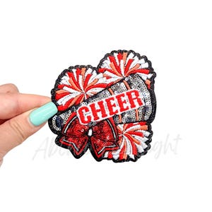 May include: Red, white, and black iron-on patch with a cheerleader megaphone, pom-poms, and the word "CHEER" in red letters.