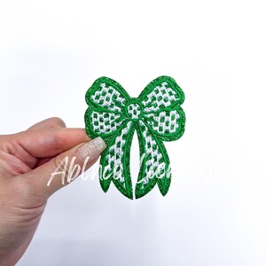 May include: Green and white checkered bow with glitter. The bow is made of fabric and has a shiny finish.