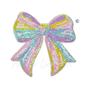 May include: A large, sequined bow in pastel colors of pink, yellow, blue, and purple. The bow is a decorative item, likely for embellishing clothing or accessories. The sequins create a shimmering effect, and the design is symmetrical.